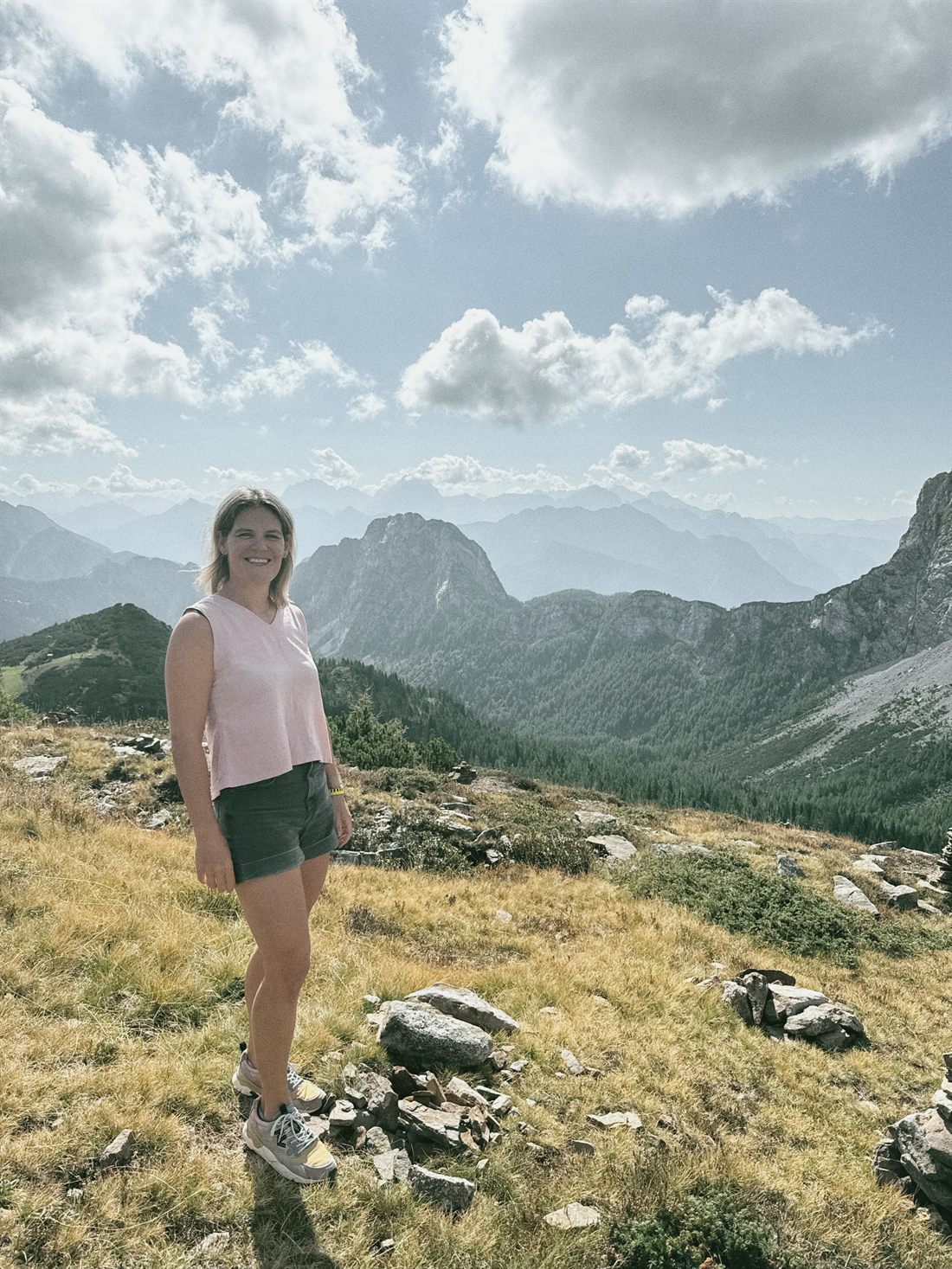 Lena Lindenmaier auf einem Bergrücken, dahinter Gipfel, Wald und Wolken